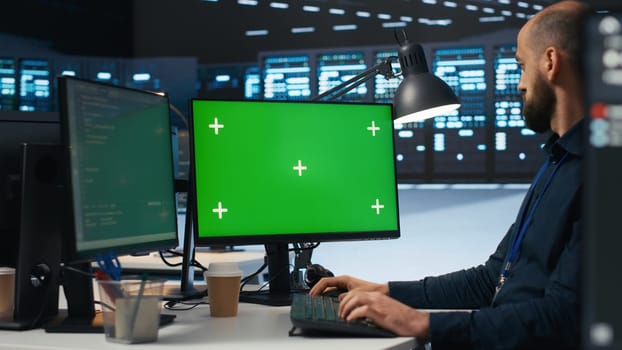 IT employee programming on green screen PC in data center housing supercomputers storing datasets. Admin writing code on mockup computer monitor to mend data center racks