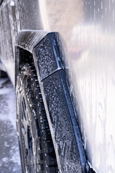 Denver, Colorado, USA-May 5, 2024-This image features a close-up view of the Tesla Cybertruck wheel and angular body design covered in soap and water during a thorough car wash, highlighting the unique textures and robust details of the electric truck.