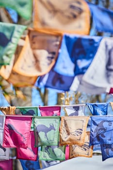 Colorful Buddhist prayer flags flutter in sunlight, symbolizing peace and wisdom, set against a clear blue sky.