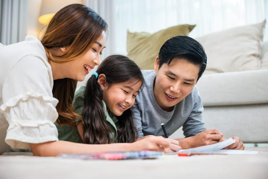 Asian family lying on floor painting with little child daughter in living room, Happy Father Mother and daughter drawing together on paper at home, Loving family activity enjoy