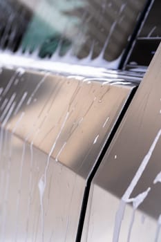 Denver, Colorado, USA-May 5, 2024-This image captures soapy water streaming beautifully down the metallic, angular side of a Tesla Cybertruck during a wash. The close-up showcases the sleek lines and unique design of the vehicle.