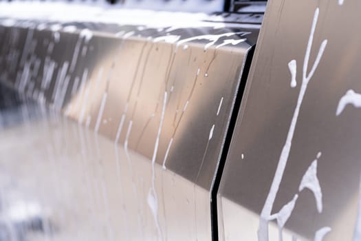 Denver, Colorado, USA-May 5, 2024-This image captures soapy water streaming beautifully down the metallic, angular side of a Tesla Cybertruck during a wash. The close-up showcases the sleek lines and unique design of the vehicle.