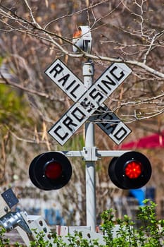 Vibrant close-up of a rural railroad crossing sign in Fort Wayne, with natural early spring backdrop.