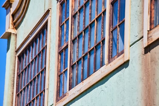 Historic Fort Wayne building with ornate arched windows and faded turquoise walls under bright sunlight.