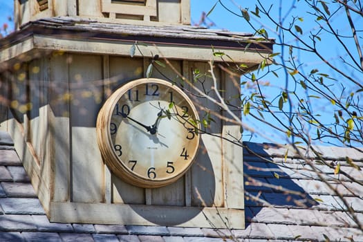 Ornate clock on stone tower, vibrant blue sky backdrop, early spring at Fort Wayne, Indiana.