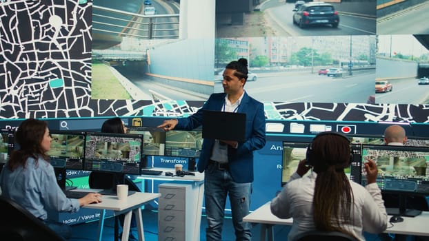 Indian supervisor handles order delivery logistics by monitoring cars route with gps coordinates and satellite navigation. Male manager locating their couriers in urban city traffic. Camera B.