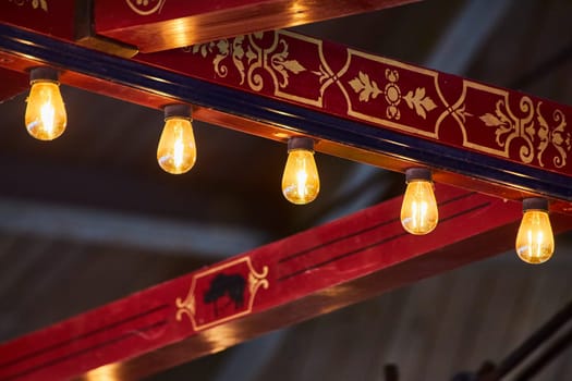 Elegant interior with ornate beam and hanging bulbs, casting warm light in a cultural setting, Indiana.