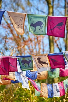 Colorful prayer flags with animal silhouettes flutter at Fort Wayne Zoo, symbolizing peace and nature.