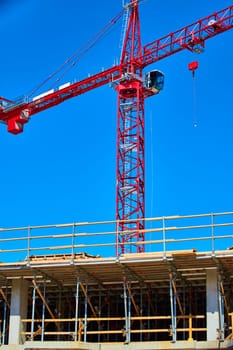 Red crane towers over bustling construction site under a clear blue sky in Downtown Fort Wayne, Indiana.