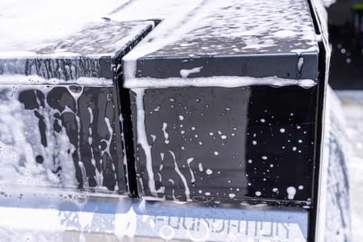 Denver, Colorado, USA-May 5, 2024-This image captures a detailed view of soap suds accumulating and dripping off the edge of a Tesla Cybertruck window during a wash, highlighting the vehicle distinct, clean lines and reflective surfaces.