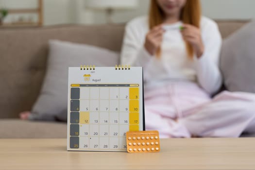 Contraception, menstruation and pregnancy concept, birth control pills asian young woman holding hormonal oral contraceptive pills with calendar, menstrual cycle. Prevention, safe virus sex disease.