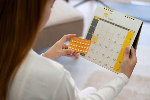 Contraception, menstruation and pregnancy concept, birth control pills asian young woman holding hormonal oral contraceptive pills with calendar, menstrual cycle. Prevention, safe virus sex disease.
