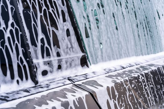 Denver, Colorado, USA-May 5, 2024-A close-up view of a Tesla Cybertruck covered in soap suds during a car wash, showcasing the flowing patterns over its angular surface and highlighting the unique design of the vehicle body.