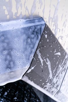 Denver, Colorado, USA-May 5, 2024-This image features a close-up view of the Tesla Cybertruck wheel and angular body design covered in soap and water during a thorough car wash, highlighting the unique textures and robust details of the electric truck.