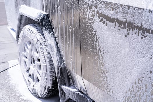 Denver, Colorado, USA-May 5, 2024-This image captures soapy water streaming beautifully down the metallic, angular side of a Tesla Cybertruck during a wash. The close-up showcases the sleek lines and unique design of the vehicle.