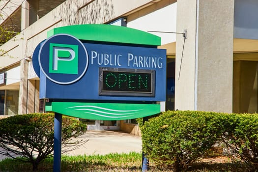 Bright public parking sign in downtown Fort Wayne on a sunny day, indicating open spaces.