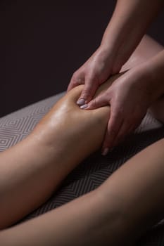 Close-up of a woman's leg massage in a salon. Vertical photo