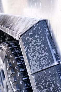 Denver, Colorado, USA-May 5, 2024-This image features a close-up view of the Tesla Cybertruck wheel and angular body design covered in soap and water during a thorough car wash, highlighting the unique textures and robust details of the electric truck.