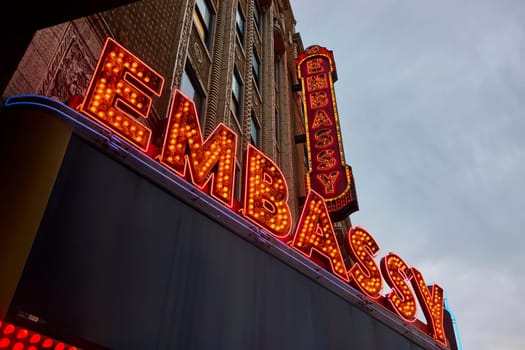 Vintage neon Embassy Theatre sign glows in twilight, Fort Wayne - classic American cinema allure.