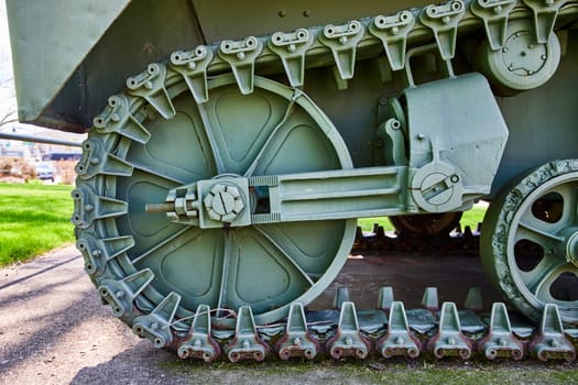 Close-up of a vintage military tank's wheel and track, highlighting robust engineering and historical might, Warsaw, Indiana.