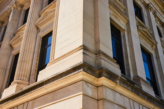 Classical yet modern architectural facade in downtown Fort Wayne, showcasing ornate columns and blue windows.