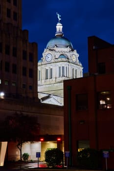 Illuminated Allen County Courthouse dome at night, flanked by modern buildings in downtown Fort Wayne.