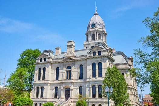 Historic Kosciusko County Courthouse in Warsaw, Indiana, showcasing 19th-century classical architecture under a clear blue sky.