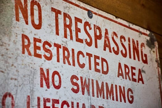 Aged NO TRESPASSING sign at Fort Wayne, emphasizing safety and boundary in bold red.