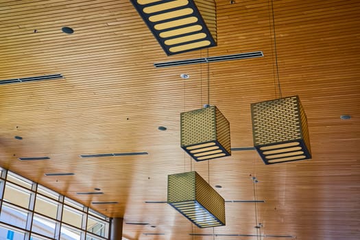 Elegant architectural design at Grand Wayne Convention Center, featuring dynamic geometric light fixtures and warm wooden ceilings.