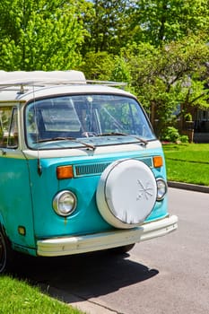 Vintage turquoise Volkswagen van on a serene suburban street in Fort Wayne, embodying nostalgia and adventure.