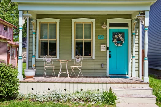 Cozy porch with turquoise door and white chairs, bathed in sunshine in a peaceful Fort Wayne neighborhood.