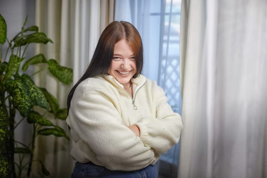 People and lifestyle concept. Body positiv. Indoor portrait of positive young Caucasian girl with chubby cheeks enjoying at home, smiling happy