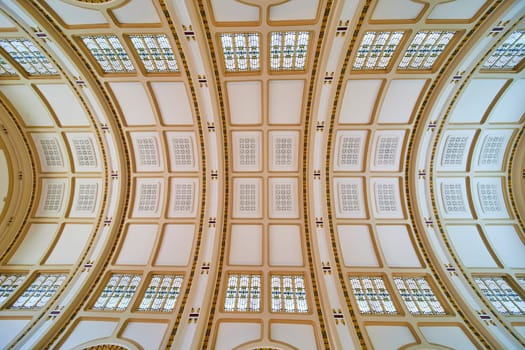 Elegant arched ceiling with stained glass at Baker Street Station, Fort Wayne, showcasing intricate gold motifs.