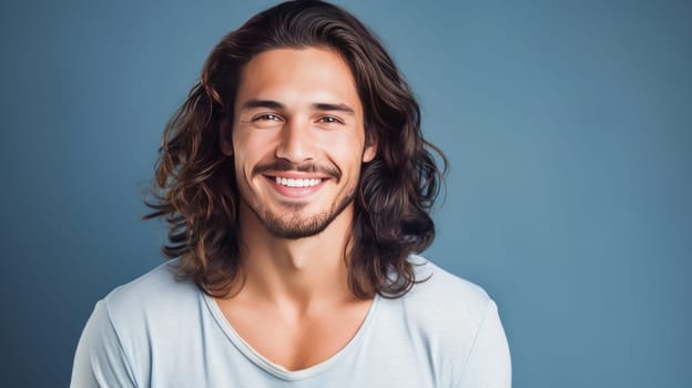 Portrait of an elegant sexy smiling Latino man with perfect skin and long hair, on a light blue background. Advertising of cosmetic products, spa treatments shampoos and hair care products, dentistry and medicine, perfumes and cosmetology for men