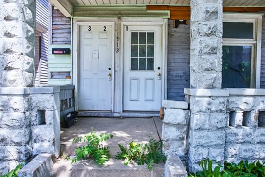 Aging triple-entry residence in Fort Wayne showcases urban decay and historic charm amidst lush greenery.