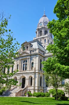 Stately Kosciusko County Courthouse in Warsaw, Indiana, showcasing classical architecture and lush greenery.