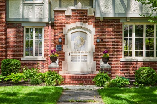 Traditional brick home in South Wayne Historic District, Fort Wayne, with vibrant floral entryway.