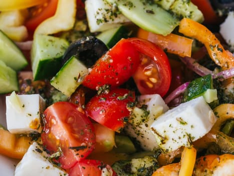 Greek salad with tomatoes, cucumbers, bell peppers, feta cheese, olives and onions close-up