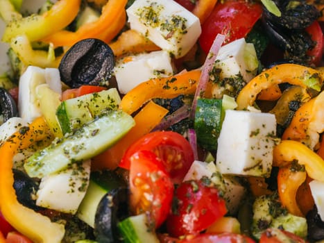 Greek salad with tomatoes, cucumbers, bell peppers, feta cheese, olives and onions close-up