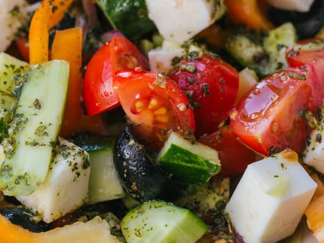 Greek salad with tomatoes, cucumbers, bell peppers, feta cheese, olives and onions close-up