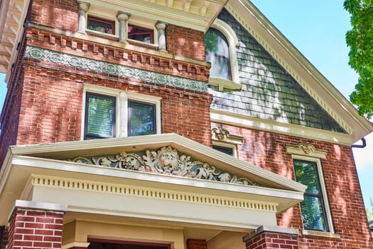 Elegant historic brick home in Fort Wayne, showcasing classical architectural details and lush greenery.