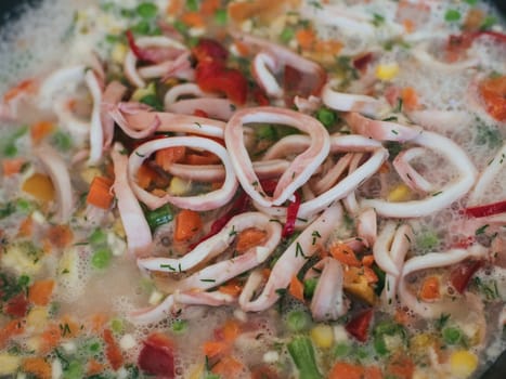 Squid rings with vegetables are cooked in a pan for a delicious dinner