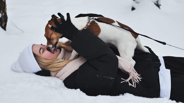 A girl playing with her Jack Russell Terrier dog in the snow