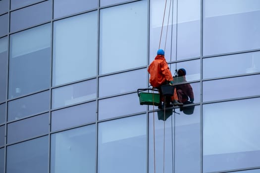 St. Petersburg, Russia - May 10, 2024. An industrial climber washes the windows of a modern office building. Selective focus.