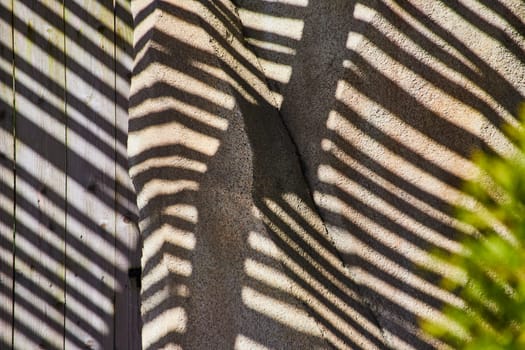 Abstract light and shadow dance on a textured wall, evoking themes of contrast and pattern, captured in Fort Wayne.