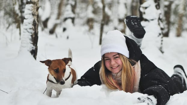 A girl playing with her Jack Russell Terrier dog in the snow