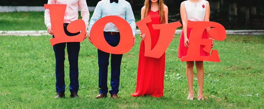 group of friends holding large wooden letters love outdoors on wedding day