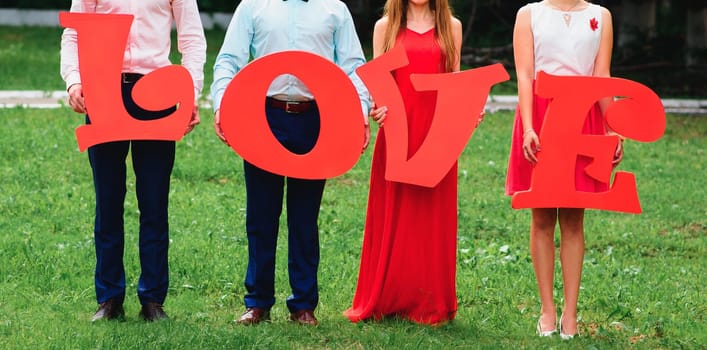 group of friends holding large wooden letters love outdoors on wedding day