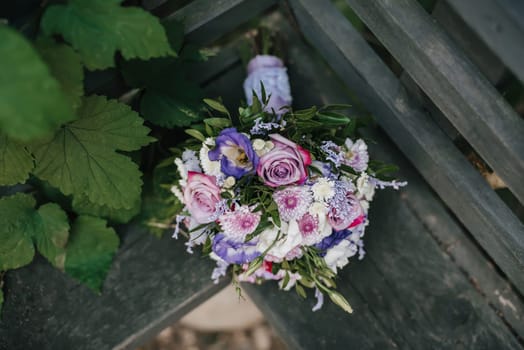 wedding bouquet of roses and pink chrysanthemums lying on the bench
