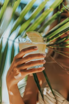 A cocktail in the hands of a girl on the beach. Selective focus. Drink.